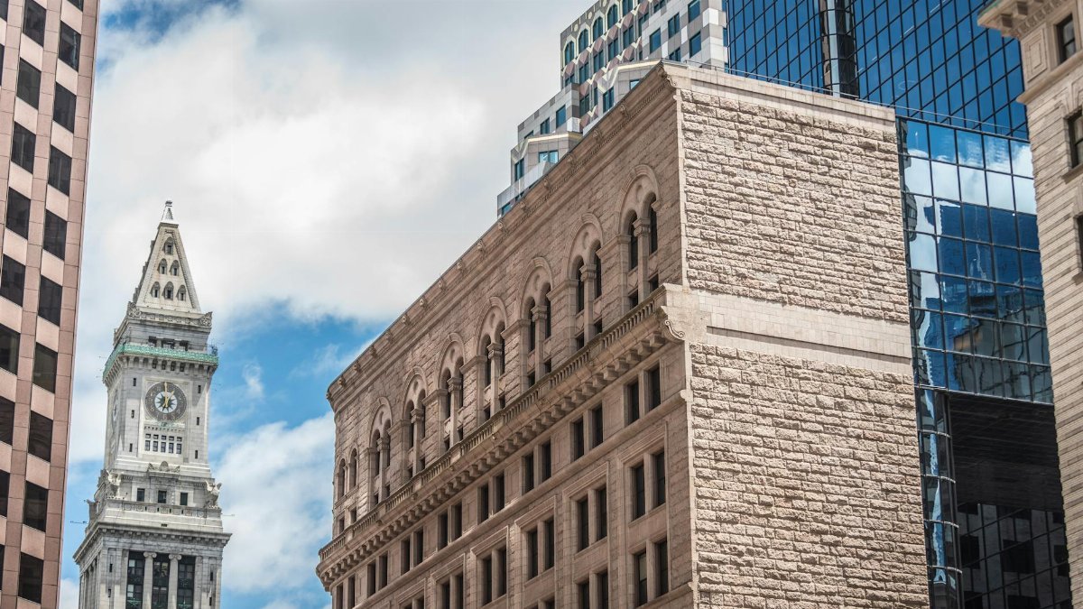 A striking view of Boston's Custom House Tower and surrounding skyscrapers against a bright sky.