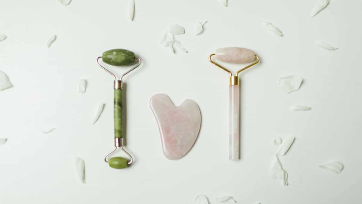 Stylish jade rollers and gua sha tools arranged on a white background, ideal for skincare routines.