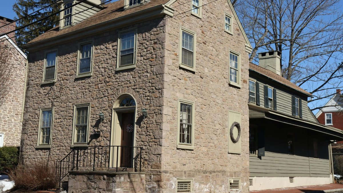 Charming stone house with colonial architecture in Newtown, PA on a sunny day.
