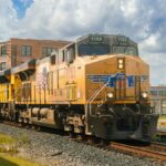 A Union Pacific locomotive travels along tracks in Houston, TX, under a vivid blue sky.