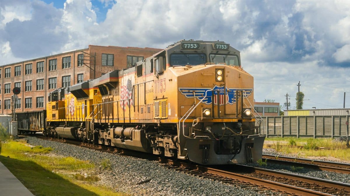 A Union Pacific locomotive travels along tracks in Houston, TX, under a vivid blue sky.