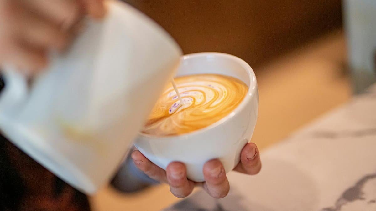 Close-up of a barista pouring latte art in a coffee shop, showcasing skillful design.
