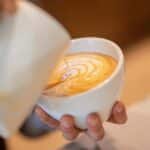 Close-up of a barista pouring latte art in a coffee shop, showcasing skillful design.