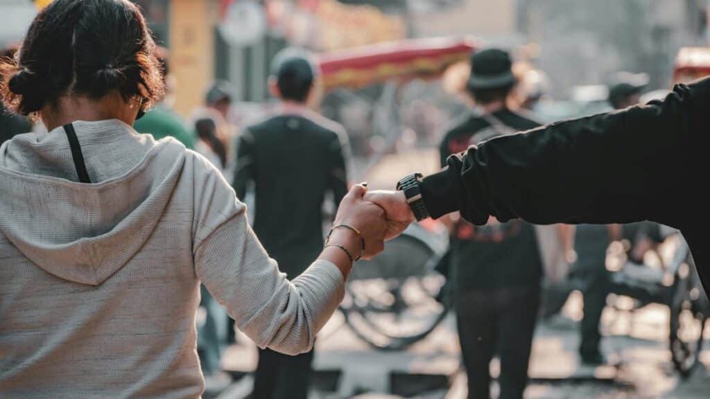 A couple holds hands while walking through a lively street in Hanoi, Vietnam.
