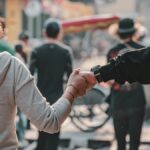 A couple holds hands while walking through a lively street in Hanoi, Vietnam.