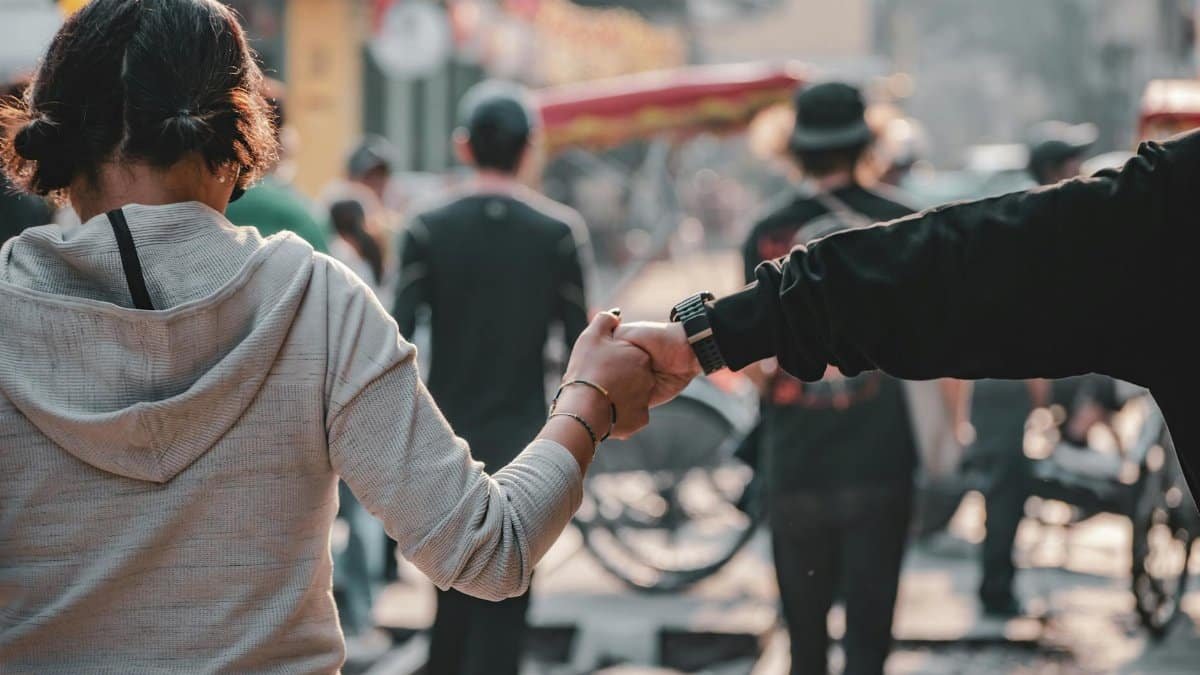 A couple holds hands while walking through a lively street in Hanoi, Vietnam.
