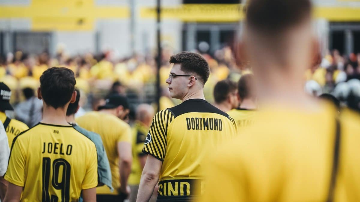Fans in yellow jerseys gather outside a stadium, supporting their team on match day.