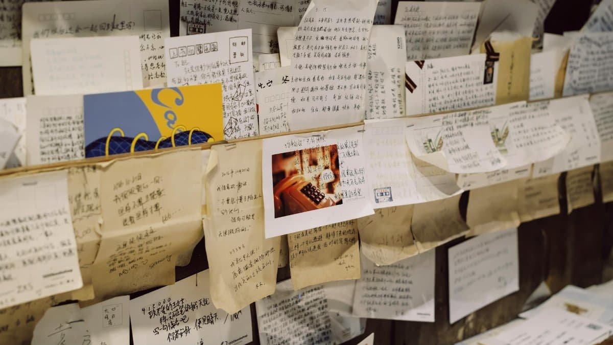 Close-up of a wall densely covered with various handwritten notes and letters.