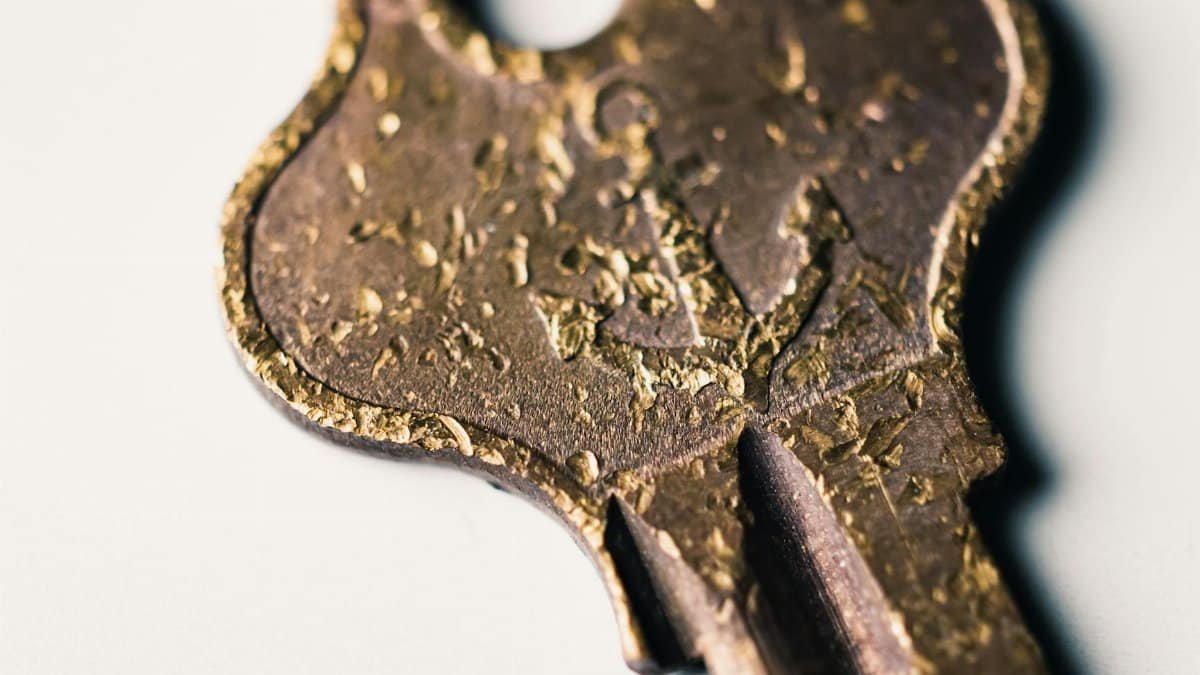 Detailed macro shot of a vintage brass key with textured patina, lying on a light background.