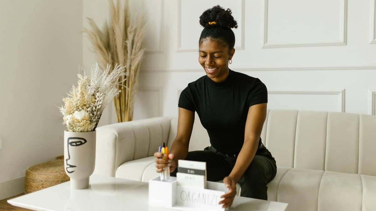 Smiling woman organizing items at home, adding pens to a holder with comfort and style.