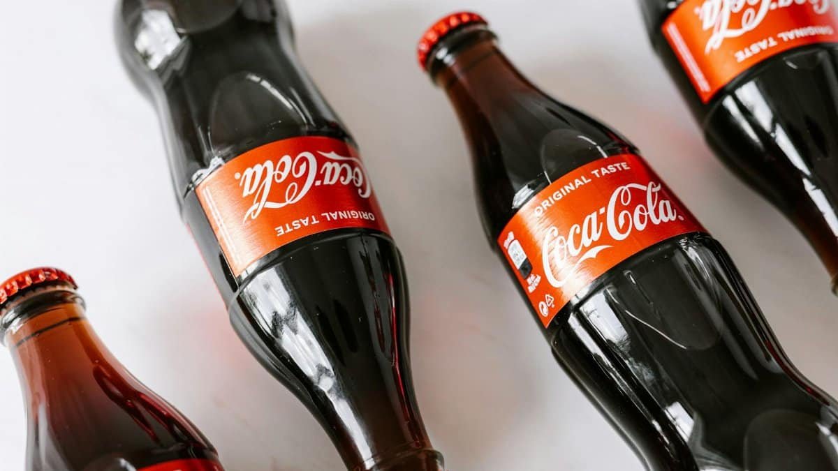 From above of glass bottles full of soft coke drink placed on white background