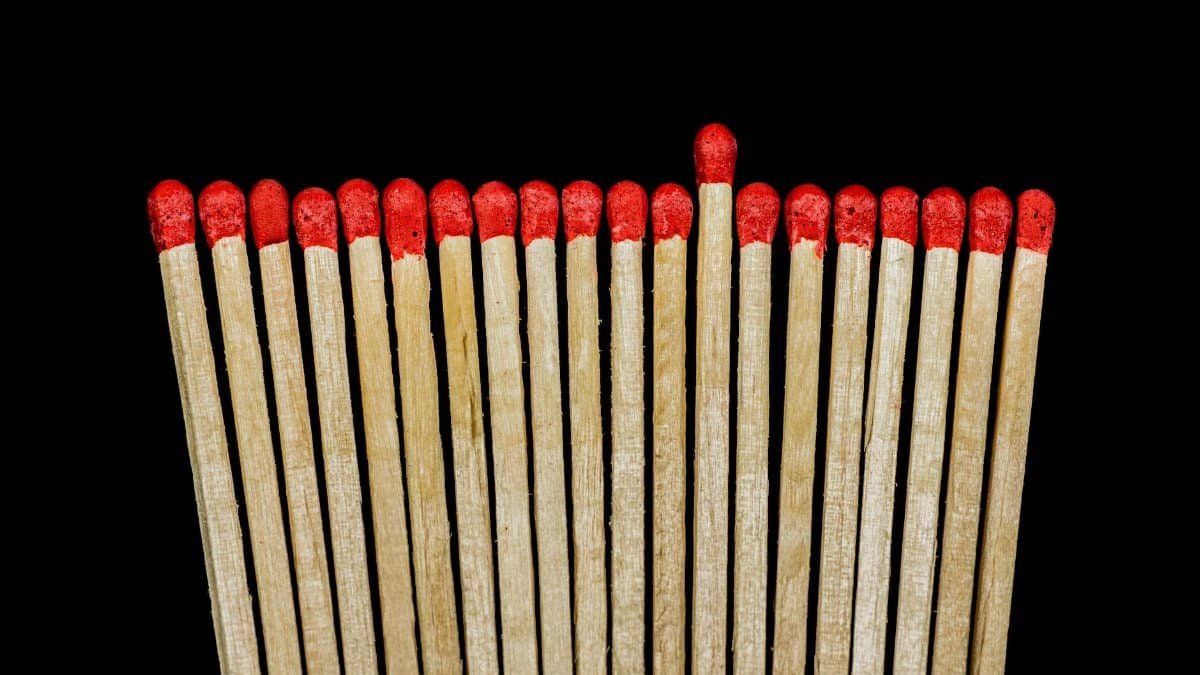 Row of red tipped wooden matches against a black background.