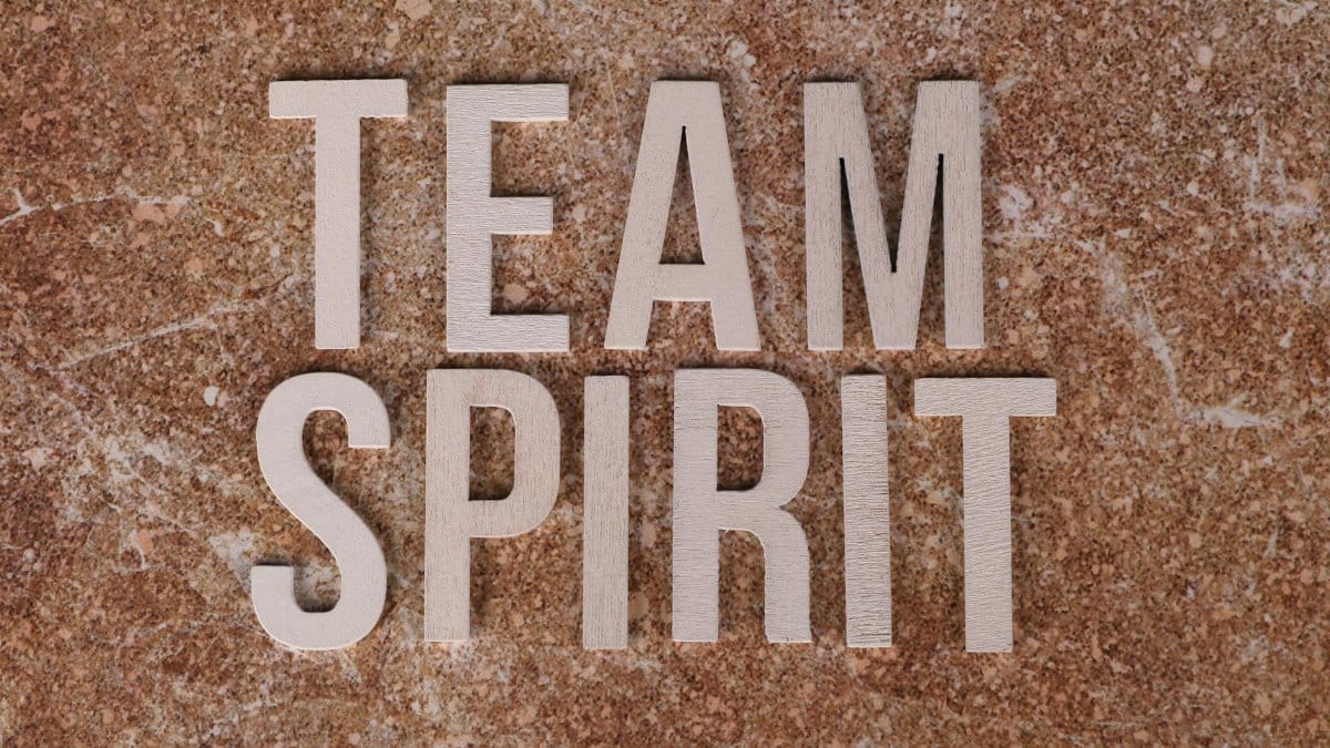 Wooden letters spelling 'Team Spirit' on a textured stone surface, symbolizing collaboration.