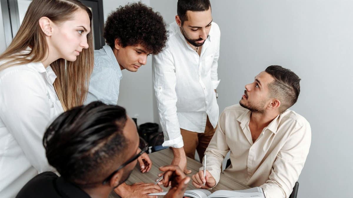 A diverse group of professionals engaged in a team discussion in a modern office setting.
