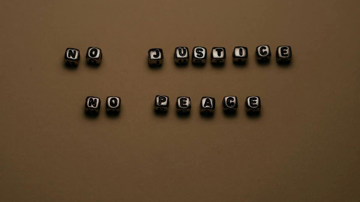 Letter blocks spelling 'No Justice No Peace' on brown background, highlighting social justice themes.