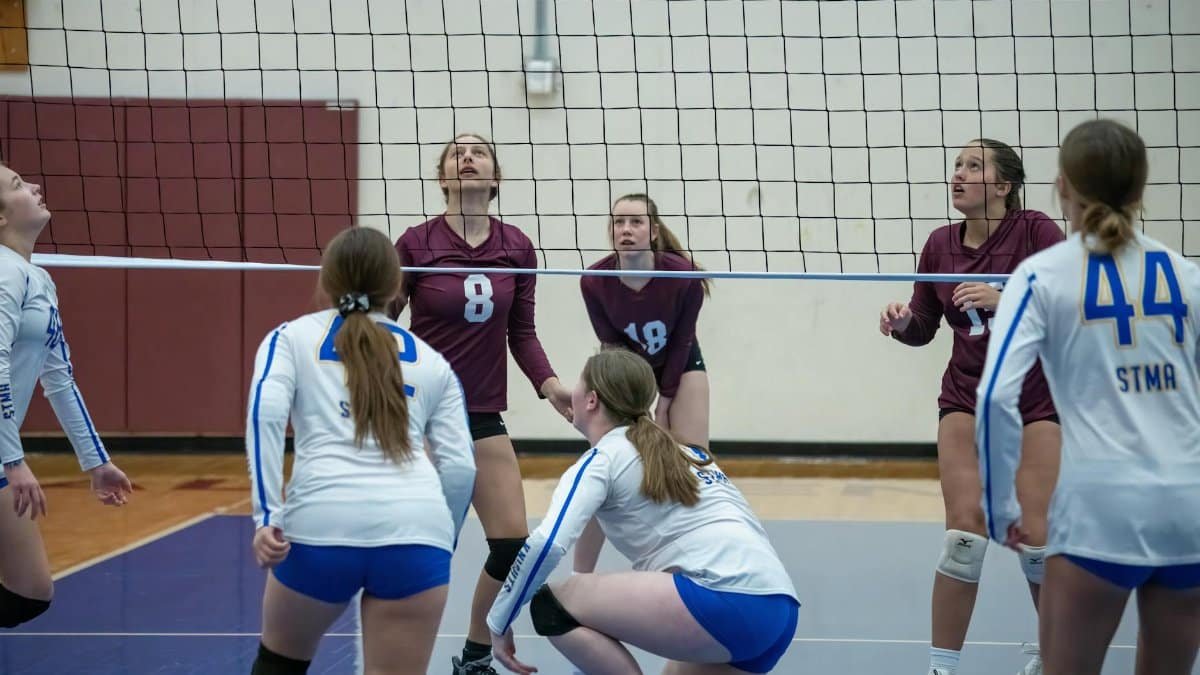 Intense volleyball match between high school teams in Rochester, MN with focused players preparing for a net play.