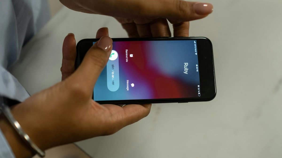 Close-up image of hands holding a smartphone receiving a call from Ruby on a marble surface.