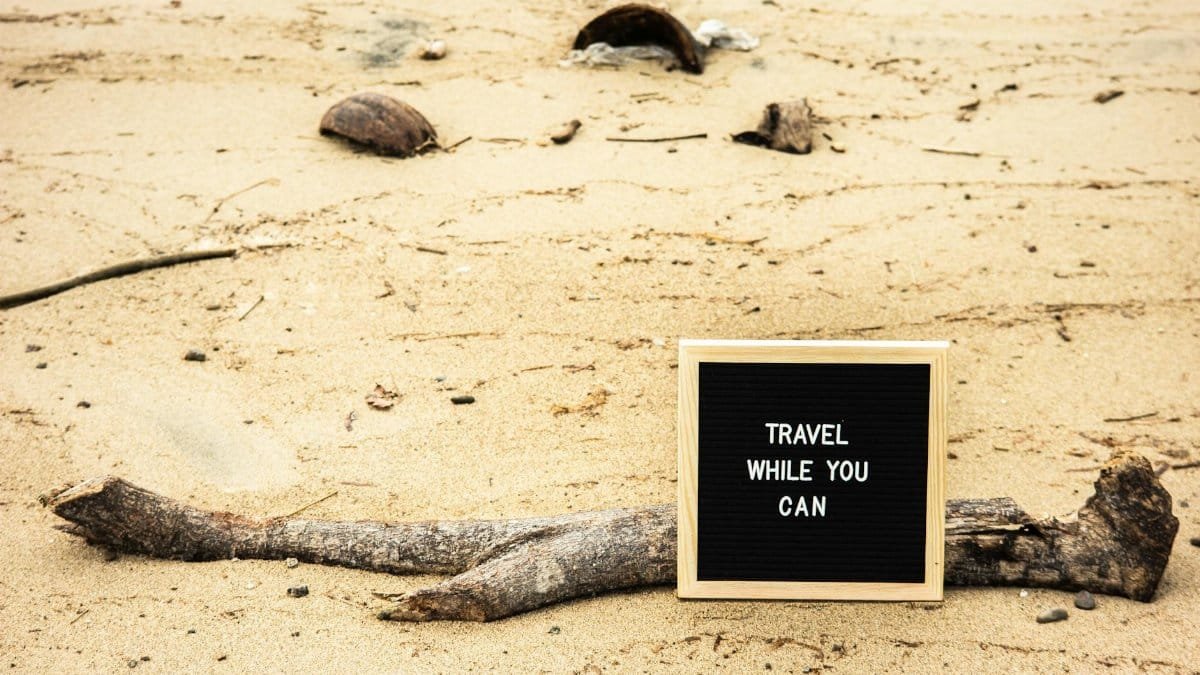 Motivational sign on sandy beach prompts travelers to seize the moment. Perfect for travel inspiration.