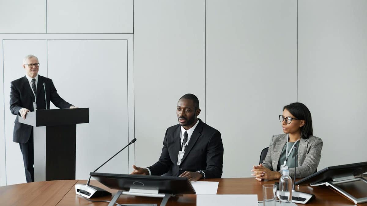 Colleagues in corporate attire discussing at a business meeting indoors.