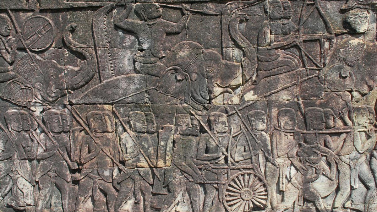 Detailed ancient stone carving depicting historical scenes from Angkor Wat, Cambodia.