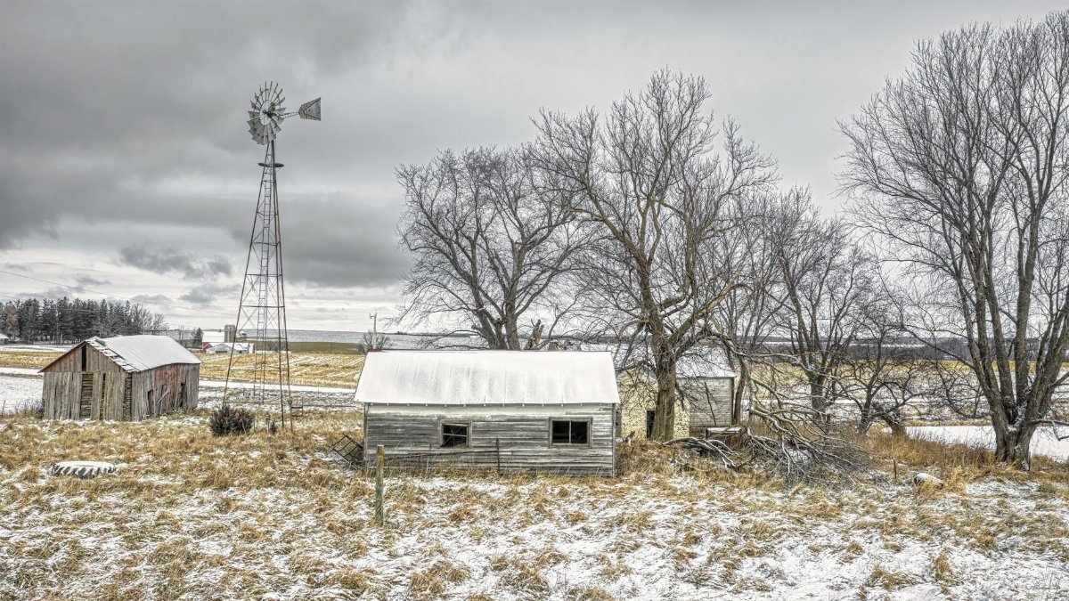 A scenic winter view of a rural farm in Minnesota with snow-covered barns and trees.