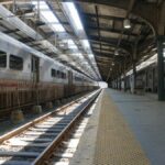 Empty railway station platform with parked trains in daylight.