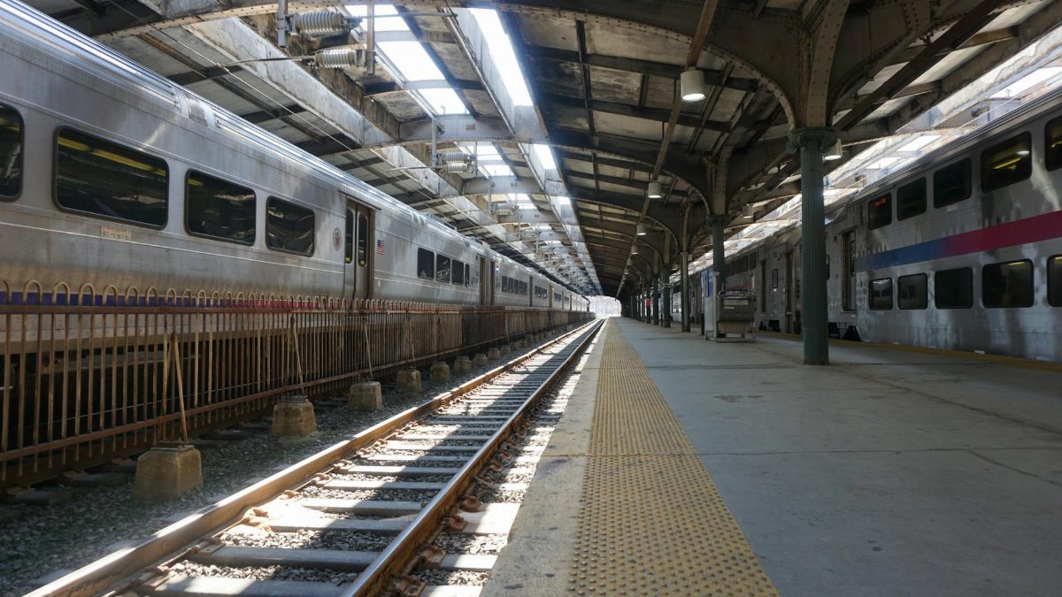 Empty railway station platform with parked trains in daylight.