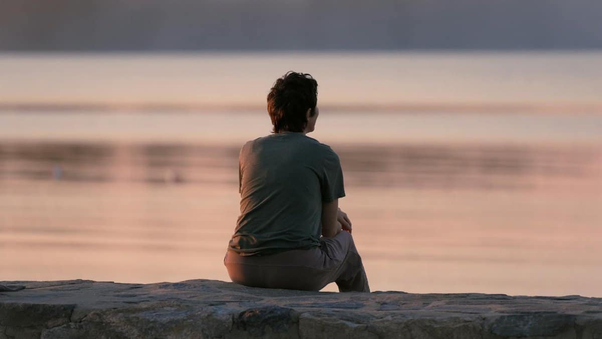Person sitting on breakwall at Cove Island Park, Stamford, enjoying a peaceful sunrise.