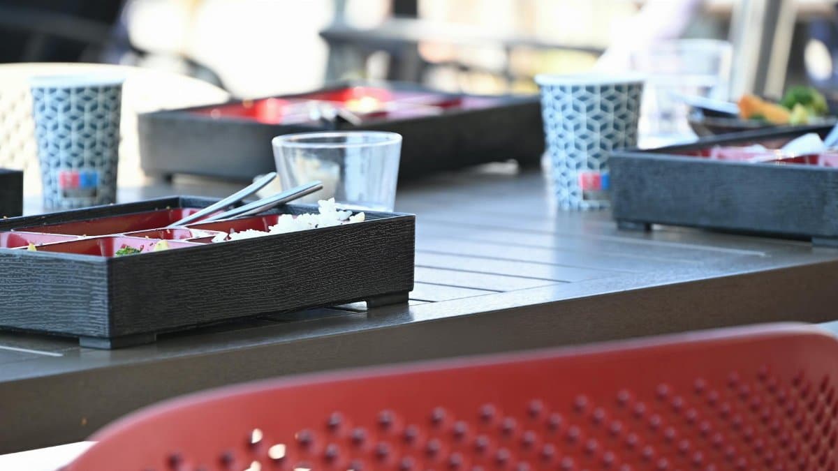 Modern outdoor dining setting with Japanese bento boxes on a table, perfect for casual meals.