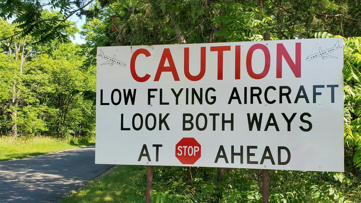 A roadside warning sign for low flying aircraft in a lush summer setting in Ohio.