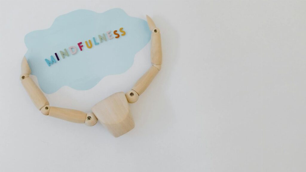 Wooden mannequin holding a mindfulness speech bubble for relaxation and mental health concepts.
