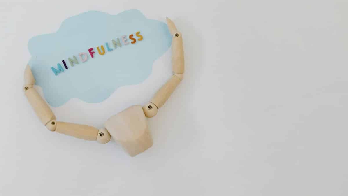 Wooden mannequin holding a mindfulness speech bubble for relaxation and mental health concepts.