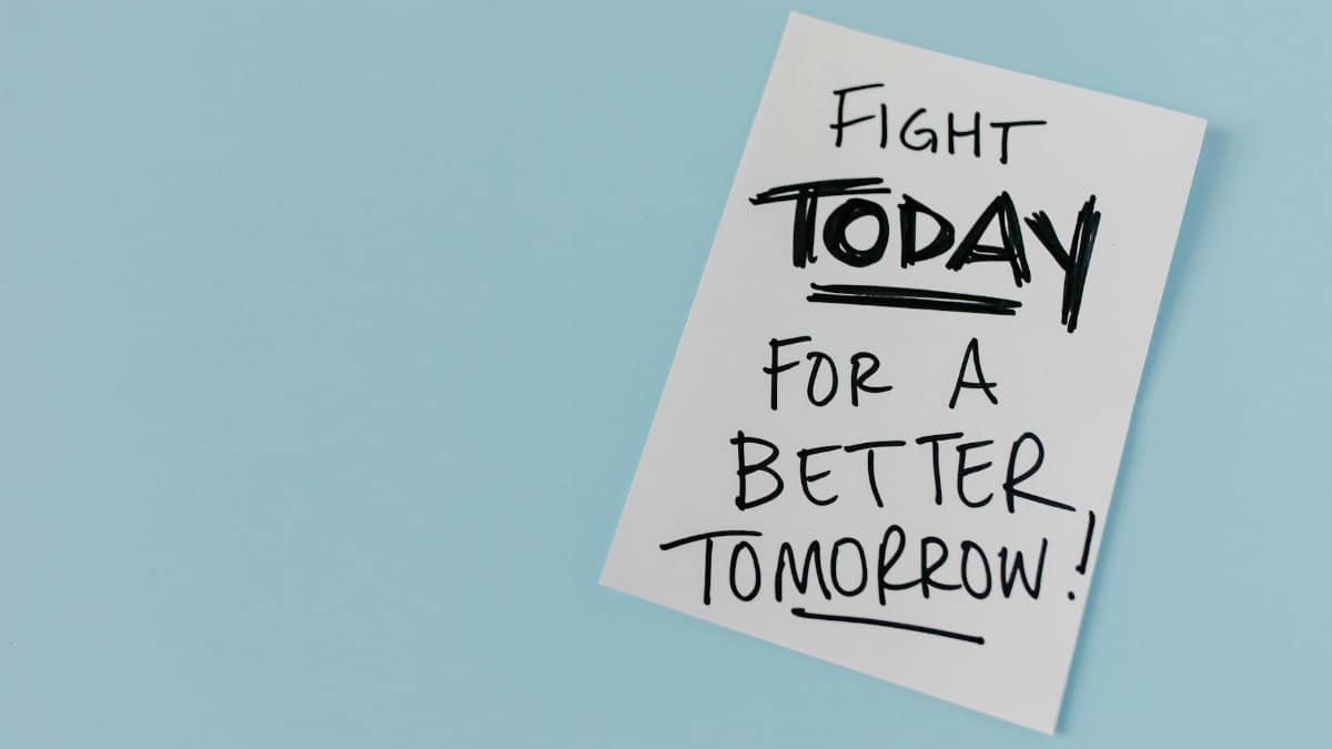 Inspirational handwritten message urging action for a better future on paper over a blue backdrop.