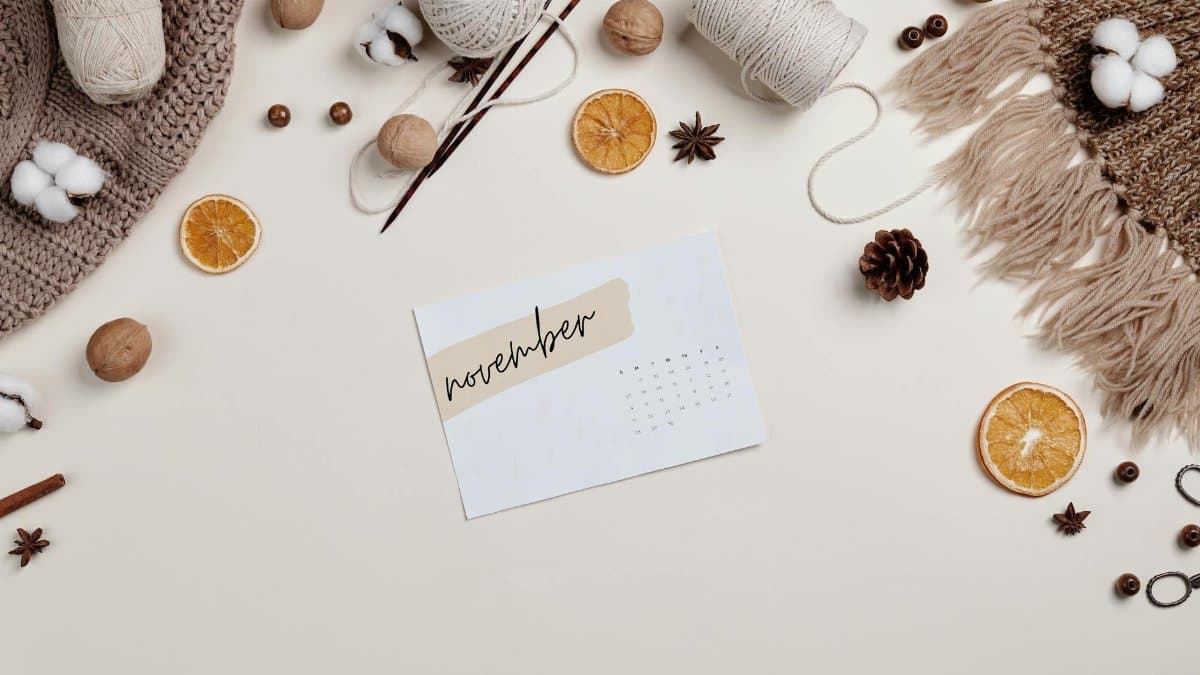 Flat lay of a cozy autumn setup with a November calendar, yarn, and dried oranges.