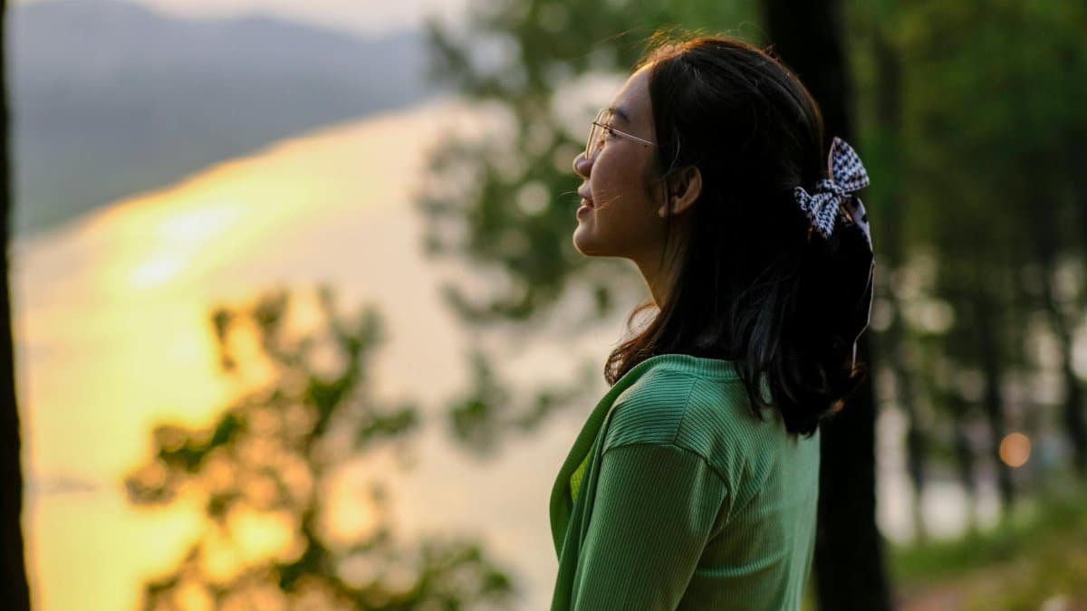 Woman enjoying a peaceful sunset by a river in Huế, Vietnam, embracing nature and tranquility.