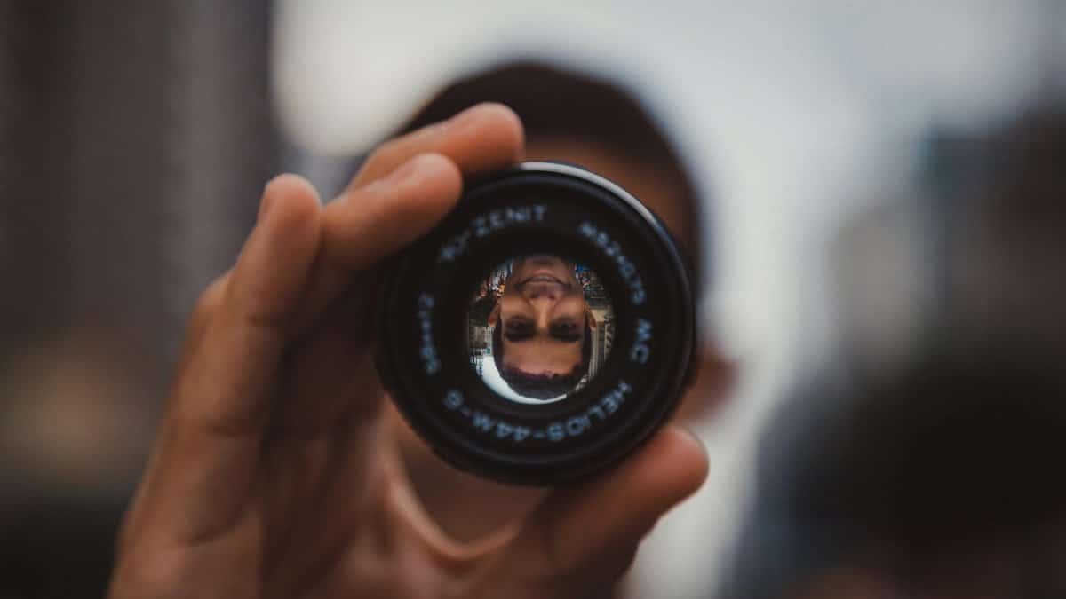 Artistic capture of a man's reflection through a camera lens showcasing creativity and perspective.
