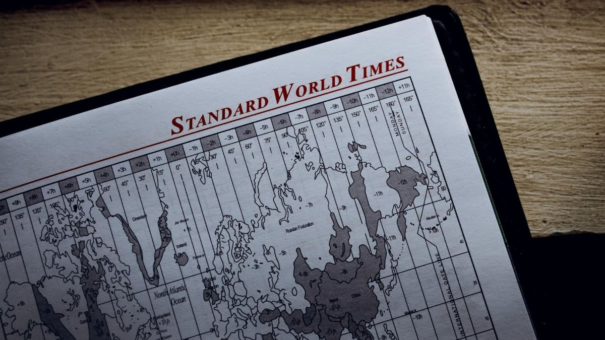 Top view of time zone illustration on page of agenda with inscription on wooden surface