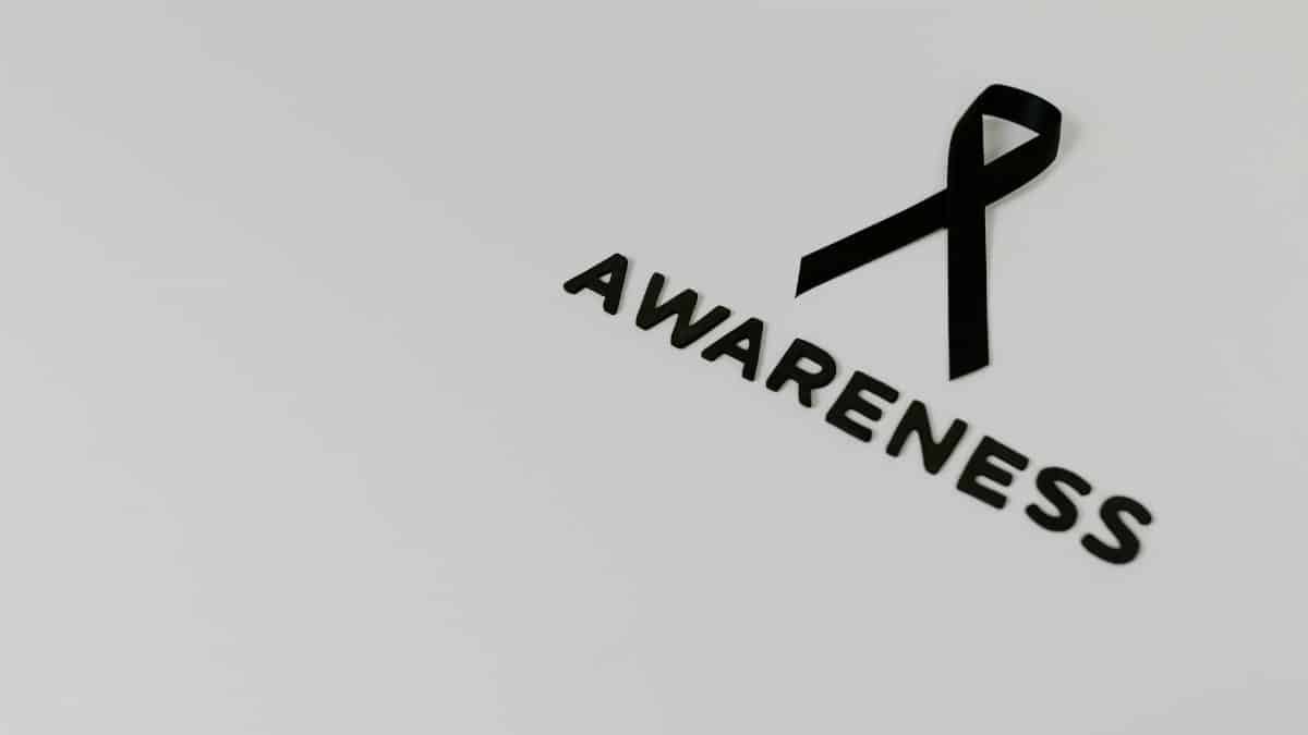 Minimalist image of a black ribbon symbolizing awareness against white background.