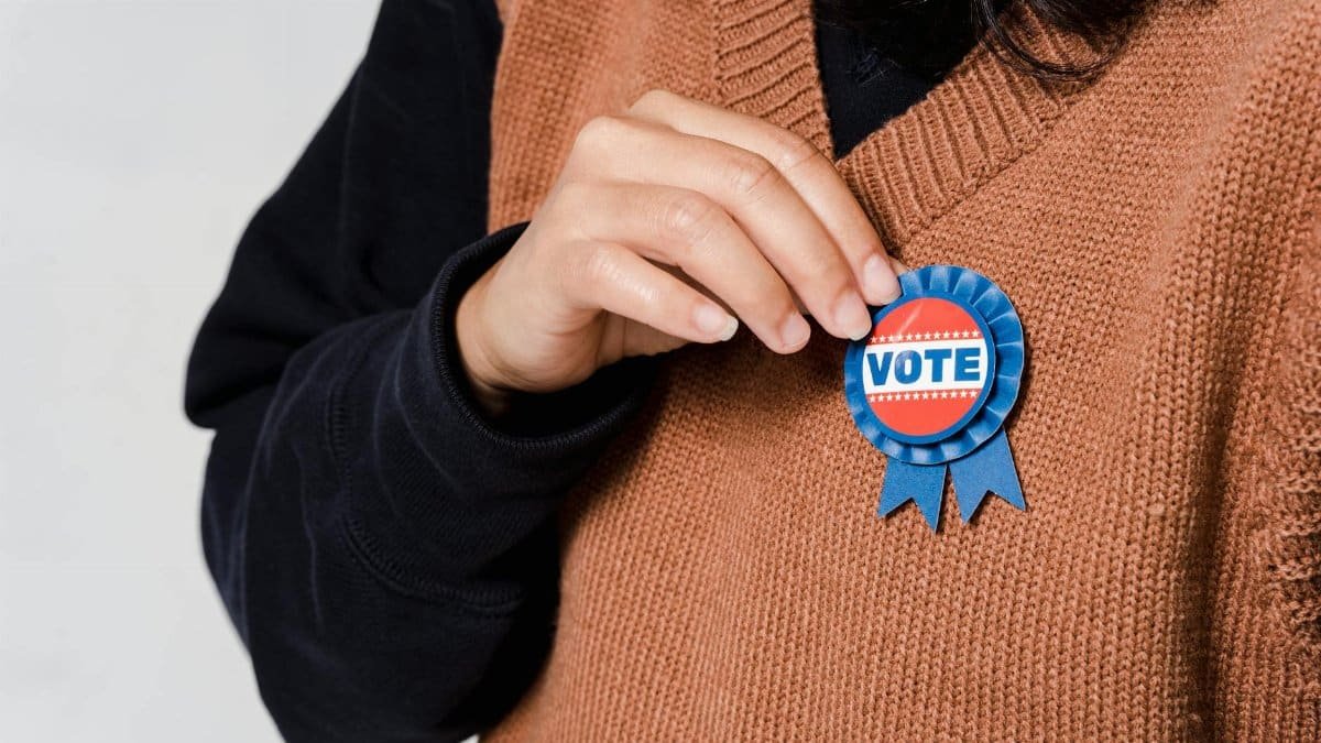 Person wearing a 'Vote' badge, symbolizing participation in democracy and elections.