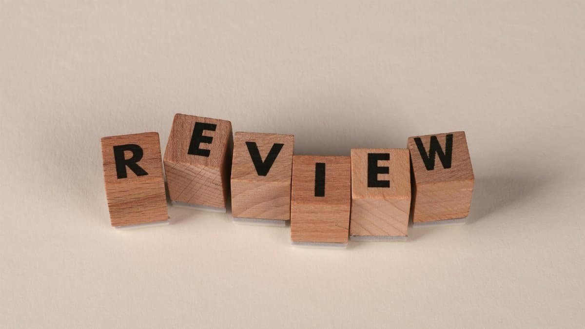 Wooden blocks with letters forming the word 'Review' on a soft pastel background.