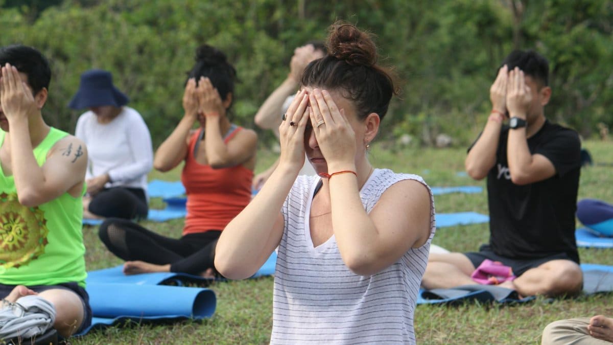 Group practicing yoga meditation outdoors at a retreat in Rishikesh, India.