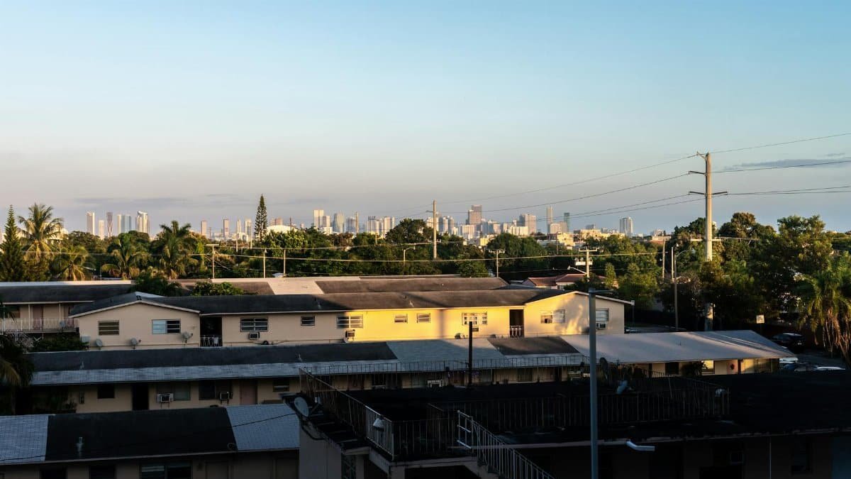 View of Miami skyline from Coral Gables at sunset with residential buildings in foreground.