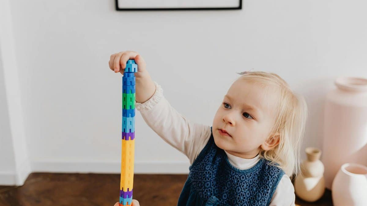 Cute toddler stacking colorful blocks at home, developing motor skills.