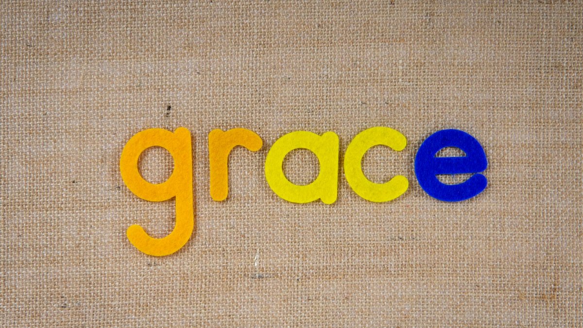 Vibrant felt letters spelling 'grace' on a textured burlap fabric background.