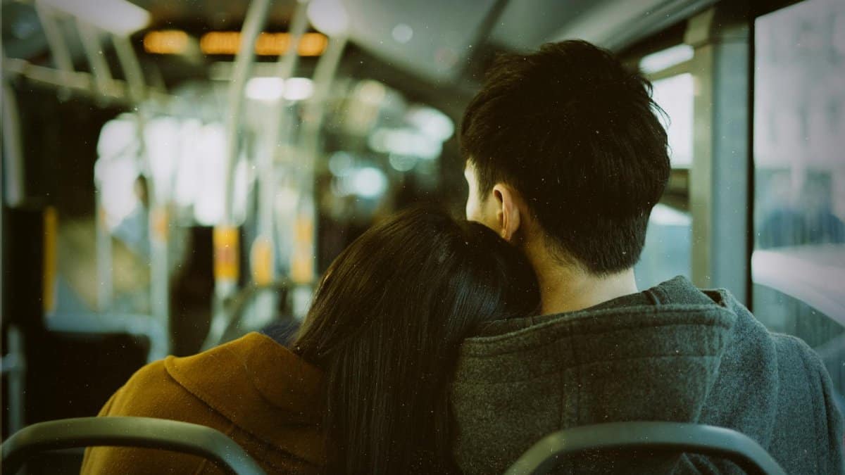 A couple resting on a city bus, showcasing affection and urban commuting life.
