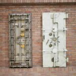 Two steel security vault doors attached to a vintage brick wall, showcasing industrial strength.