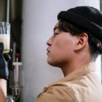 A brewmaster inspects craft beer in a glass, focusing on quality control in the brewery.