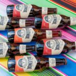 A collection of craft beer bottles arranged on a colorful Mexican tablecloth, perfect for cultural and beverage themes.