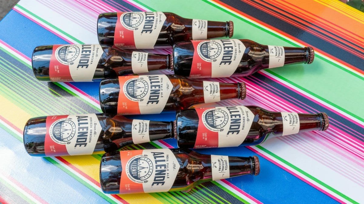 A collection of craft beer bottles arranged on a colorful Mexican tablecloth, perfect for cultural and beverage themes.