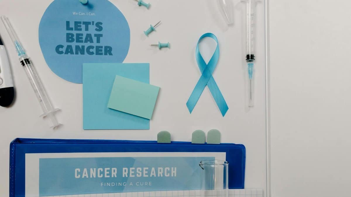 Flat lay showing cancer awareness items with blue ribbon and research tools.